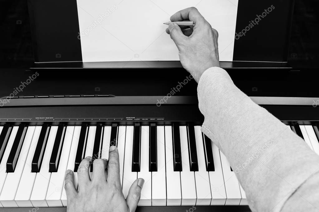Composer writing music at a piano in a studio