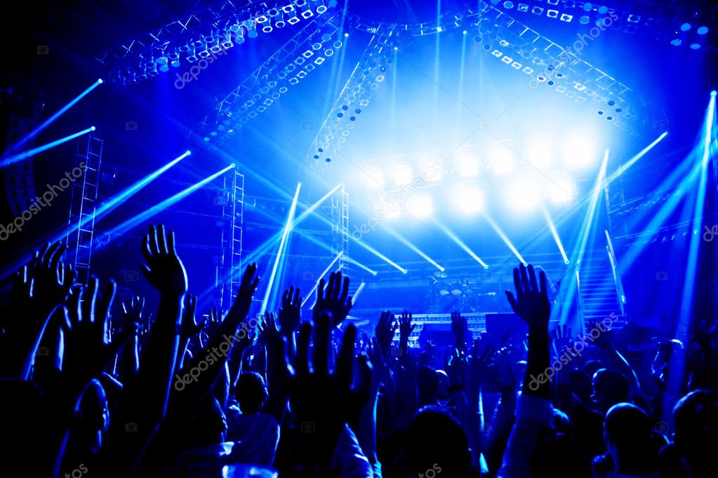 Youth group jumping and praising at a concert with colorful lights