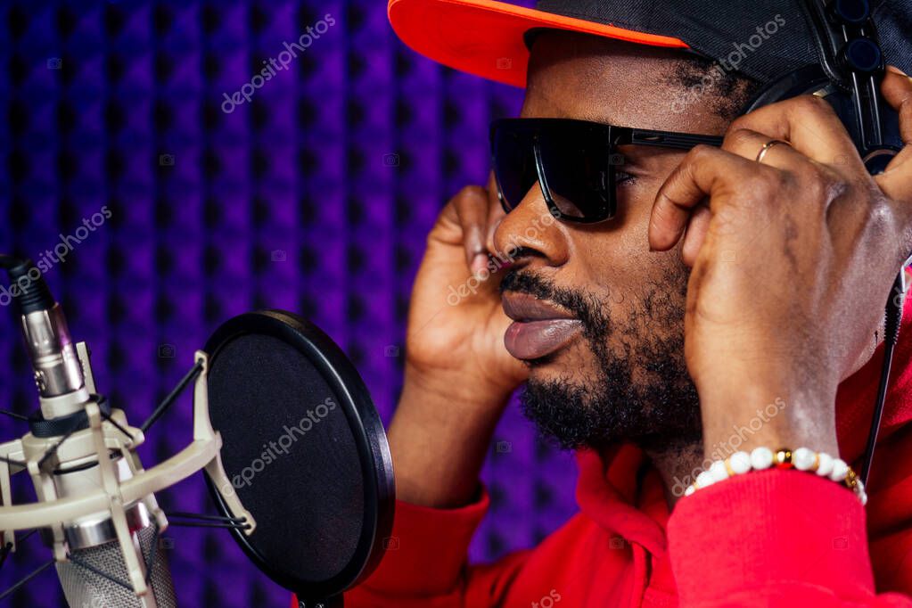 Artist recording hip-hop vocals in a studio with headphones on