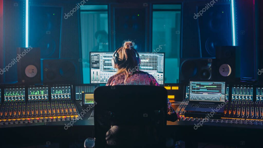 Music producer working at a studio desk with headphones and a laptop