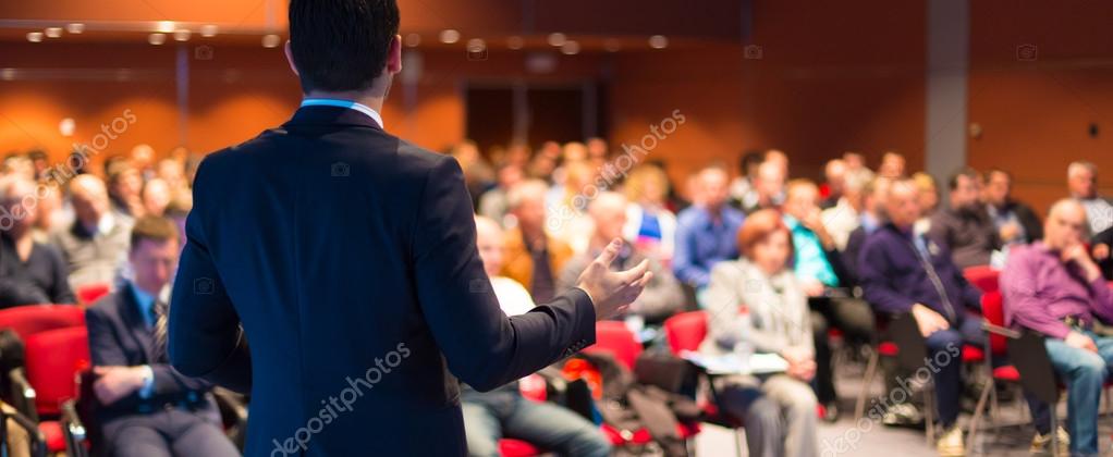 Motivational speaker on stage addressing an audience