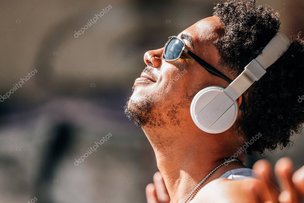 Person listening to music on headphones while browsing a playlist on a laptop